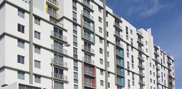 Exterior of tall, white, contemporary concrete multi-story apartment building with Juliet balconies.